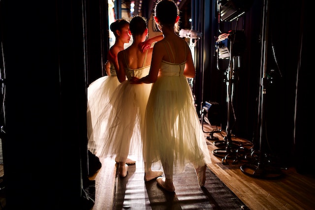 three ballerinas in white tutus backstage